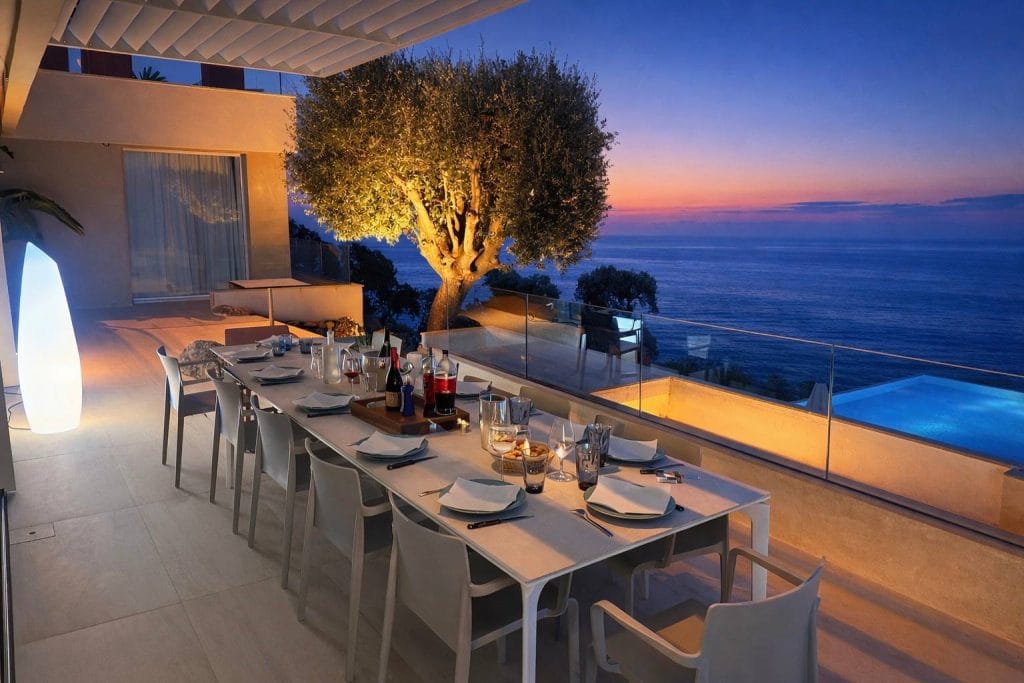 Table dressée en terrasse avec vue mer au coucher du soleil