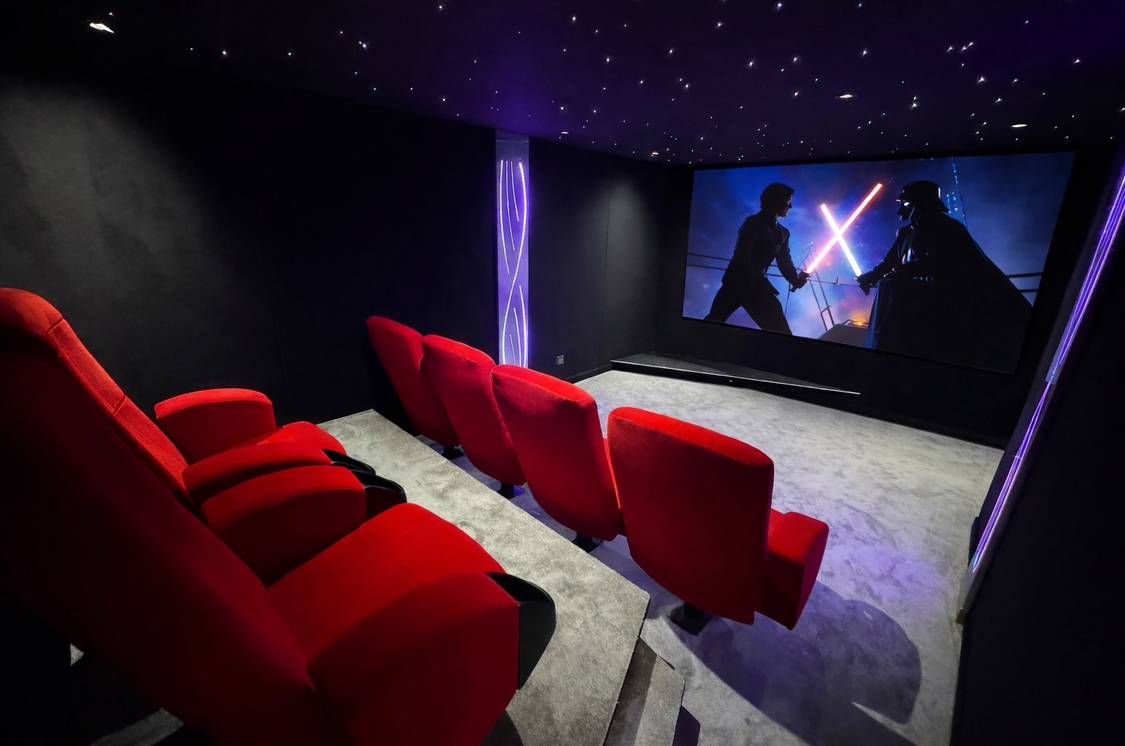 Salle de cinéma privée avec fauteuils rouges et grand écran