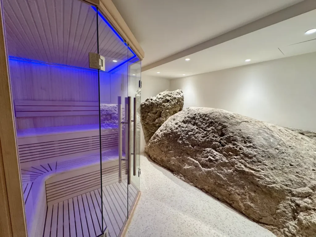 Sauna en bois avec éclairage bleu, intégré à un espace bien-être minéral