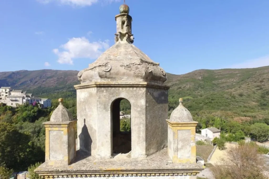 Église en pierre avec échafaudage visible sur le clocher en cours de restauration