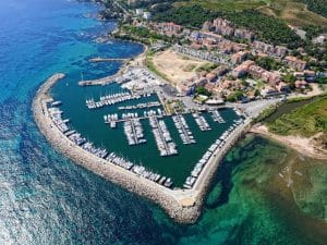 Vue aérienne du port de plaisance de Solenzara avec bateaux, commerces et centre urbain en bord de mer